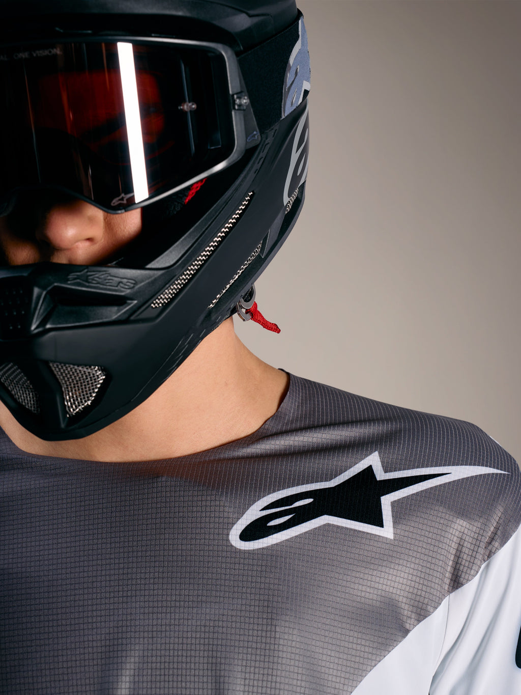Alpinestars A-Supra Elite-trøje i gråtonet mikroperforeret stof med hvidt logo og sort MTB-hjelm.