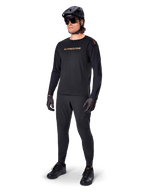 Alpinestars A-Aria Polartec Switch langærmet jersey, sort, bronzefarvet branding på brystet, mountainbiker iført sort hjelm og solbriller, teknisk cykeltøj til trailkørsel