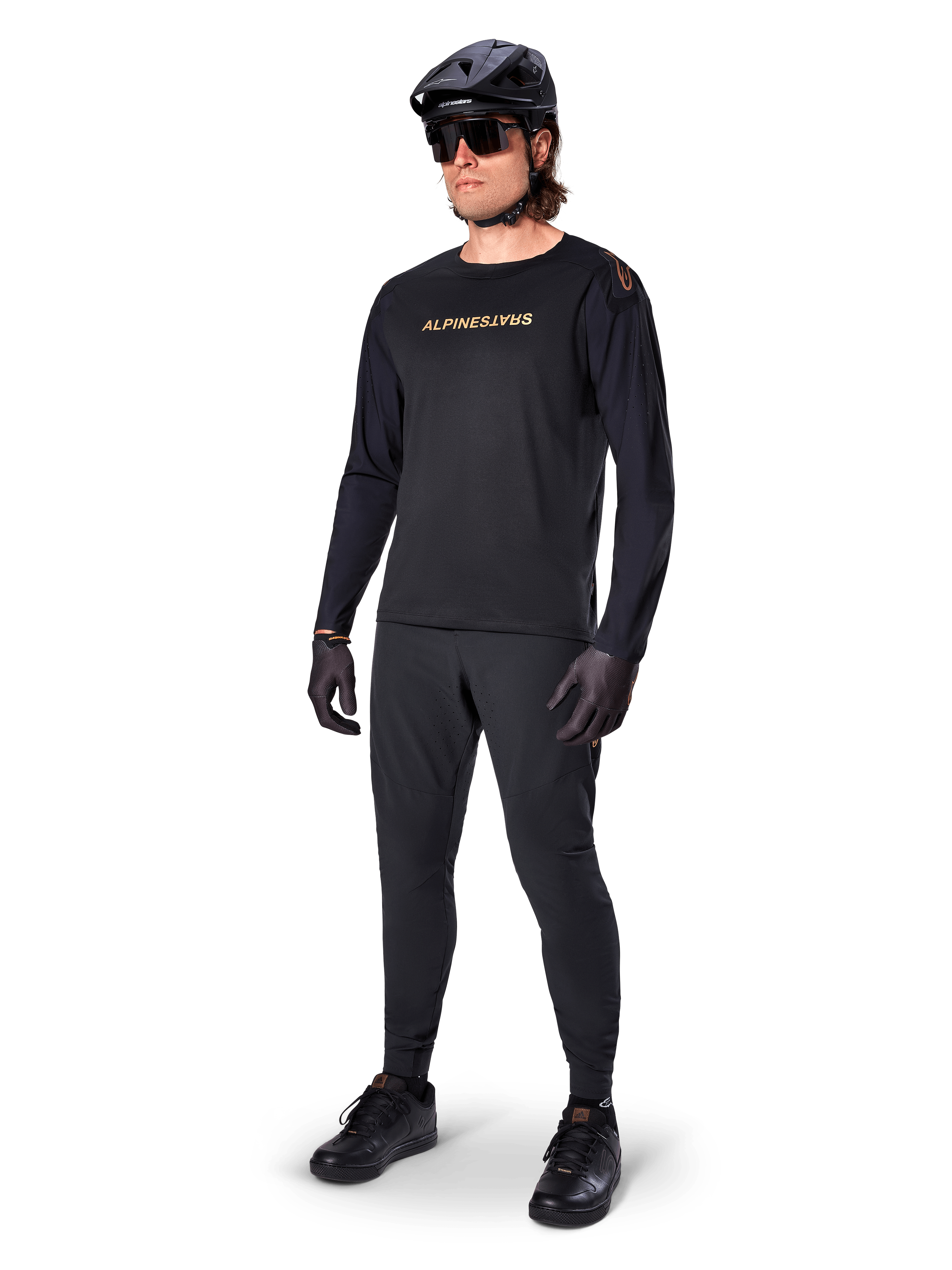 Alpinestars A-Aria Polartec Switch langærmet jersey, sort, bronzefarvet branding på brystet, mountainbiker iført sort hjelm og solbriller, teknisk cykeltøj til trailkørsel