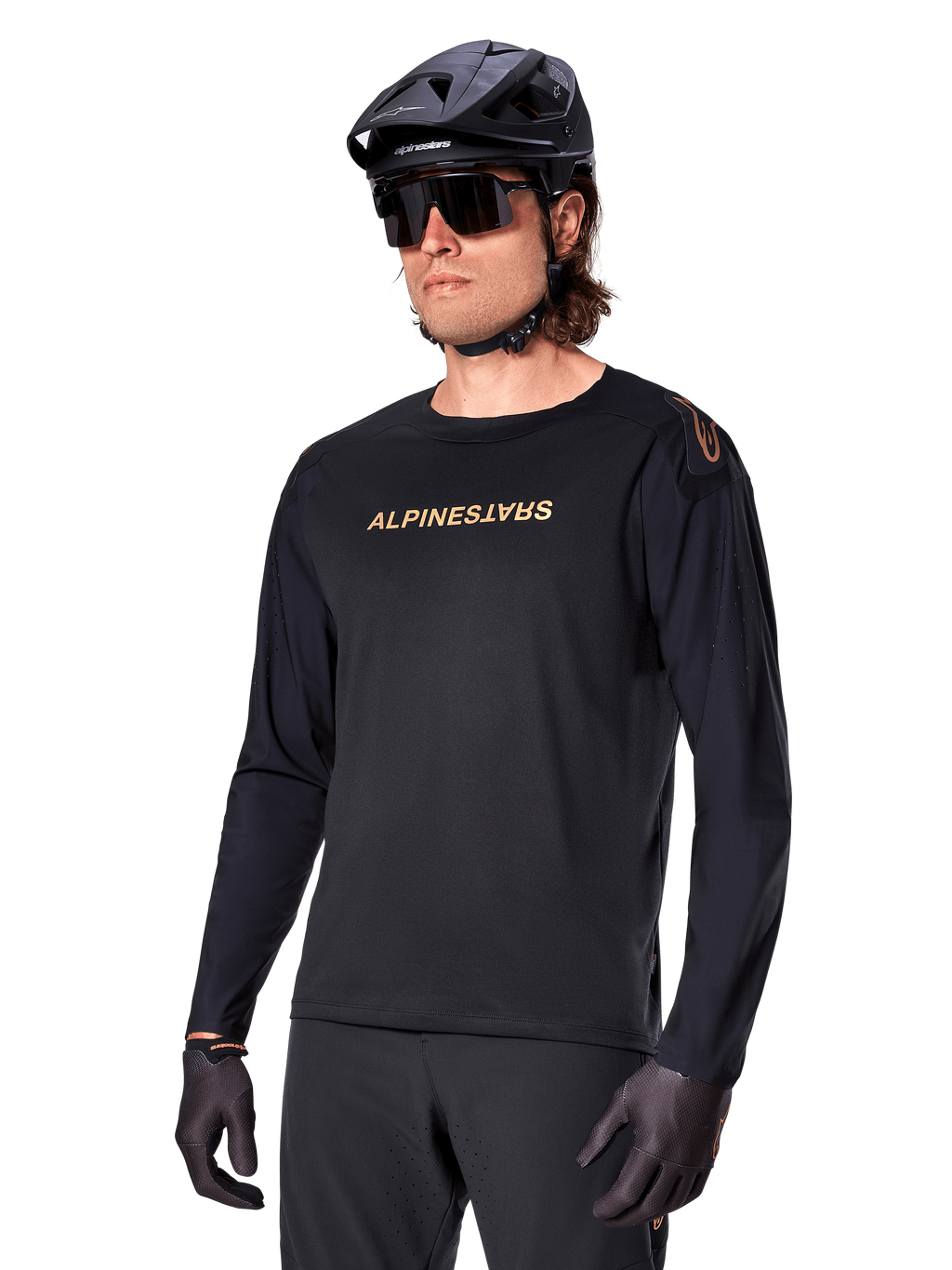 Alpinestars A-Aria Polartec Switch langærmet trøje, sort med guldlogo, MTB mountainbike-beklædning, iført sort hjelm og solbriller, med laserskåret ventilation på ærmerne og svedtransporterende Polartec-stof til terrænkørsel