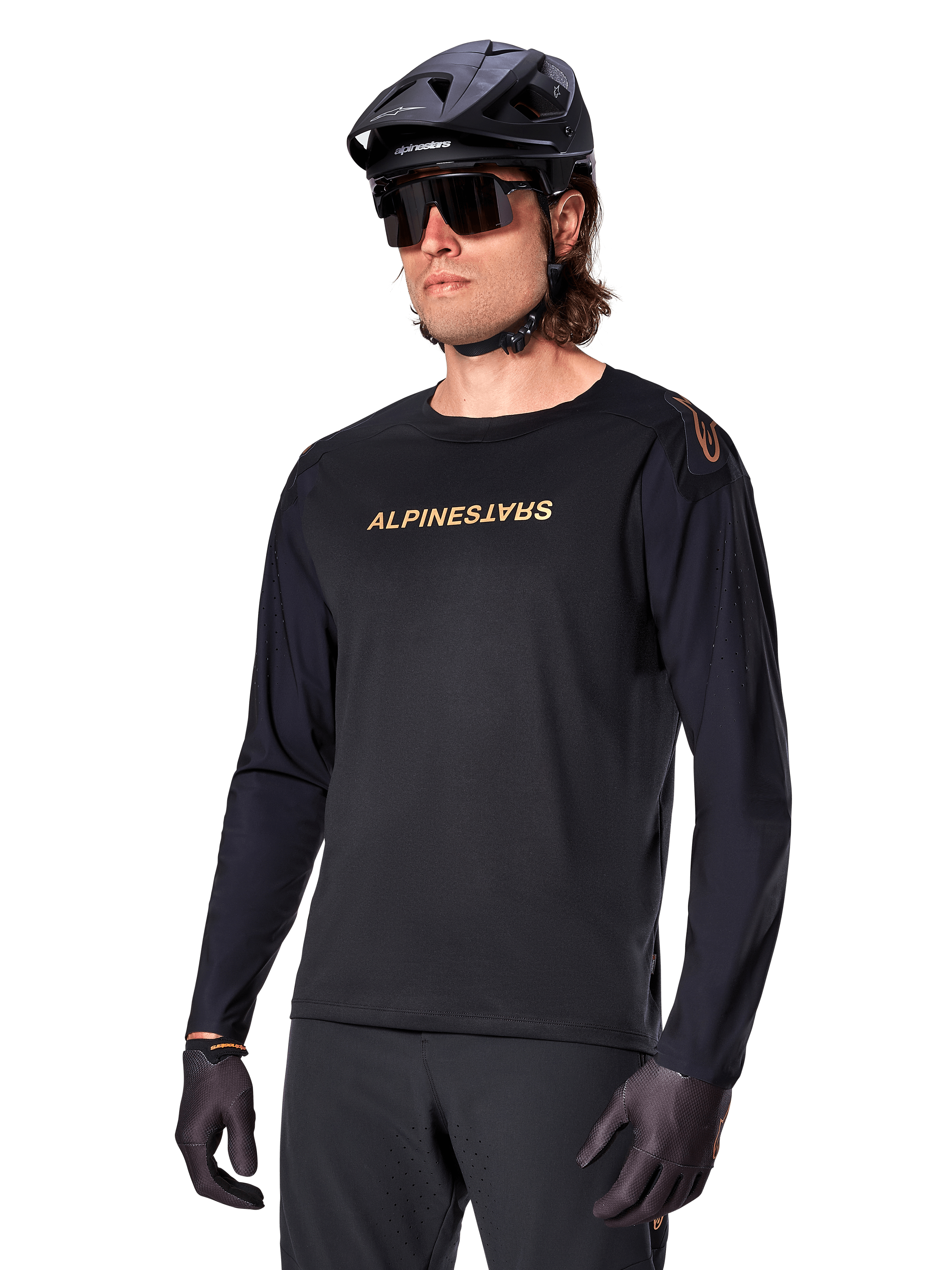 Alpinestars A-Aria Polartec Switch langærmet trøje, sort med guldlogo, MTB mountainbike-beklædning, iført sort hjelm og solbriller, med laserskåret ventilation på ærmerne og svedtransporterende Polartec-stof til terrænkørsel