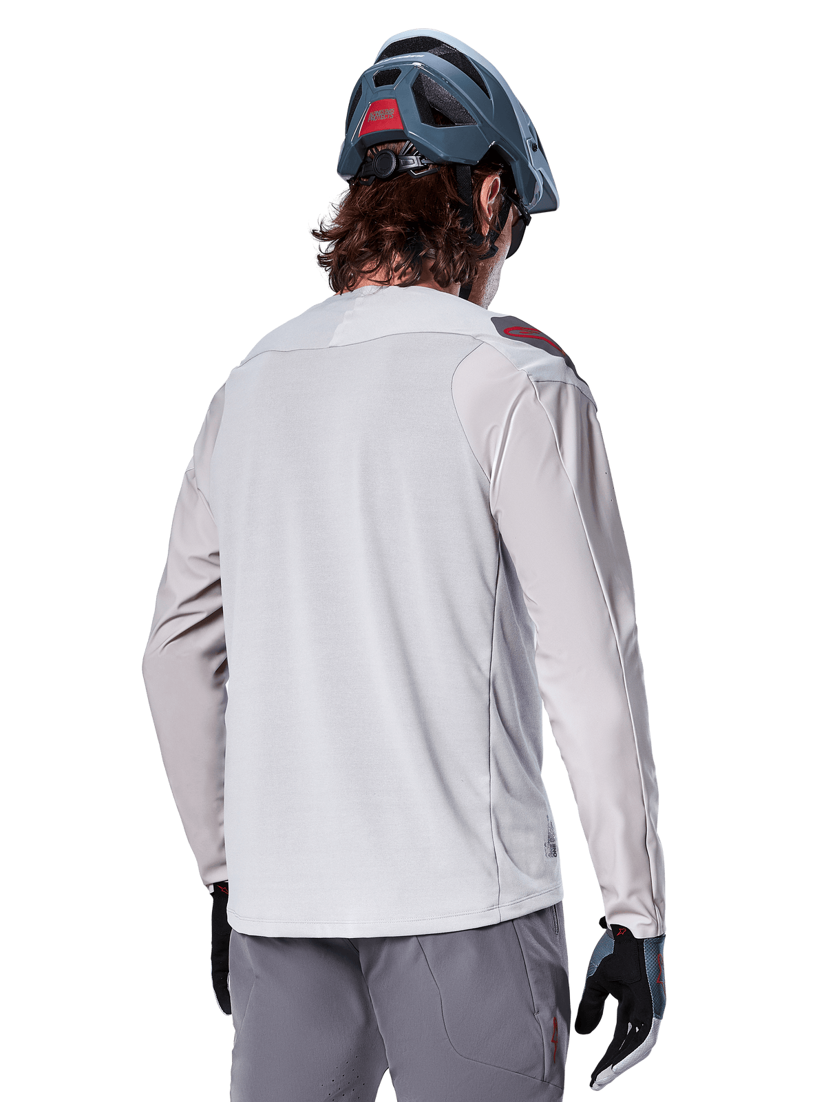Alpinestars A-Aria Polartec Switch langærmet jersey, lysegrå, set bagfra på en rytter, båret med blå mountainbike-hjelm og grå bukser, funktionelt mountainbike-udstyr til terrænkørsel