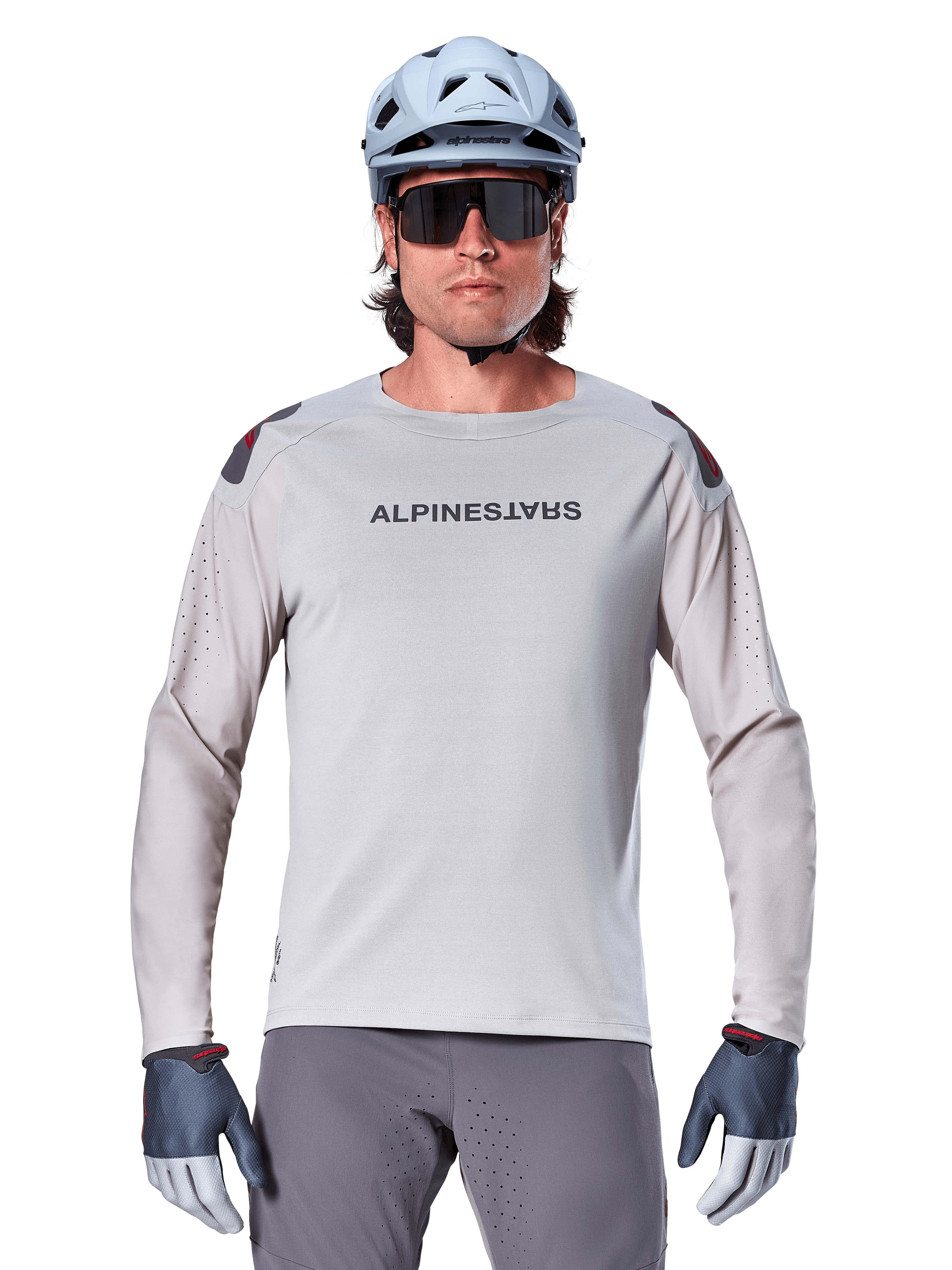 Alpinestars A-Aria Polartec Switch langærmet jersey, lysegrå mountainbike-jersey med laserperforeringer på ærmerne og brandnavn på brystet, båret med lyseblå hjelm, solbriller og grå handsker