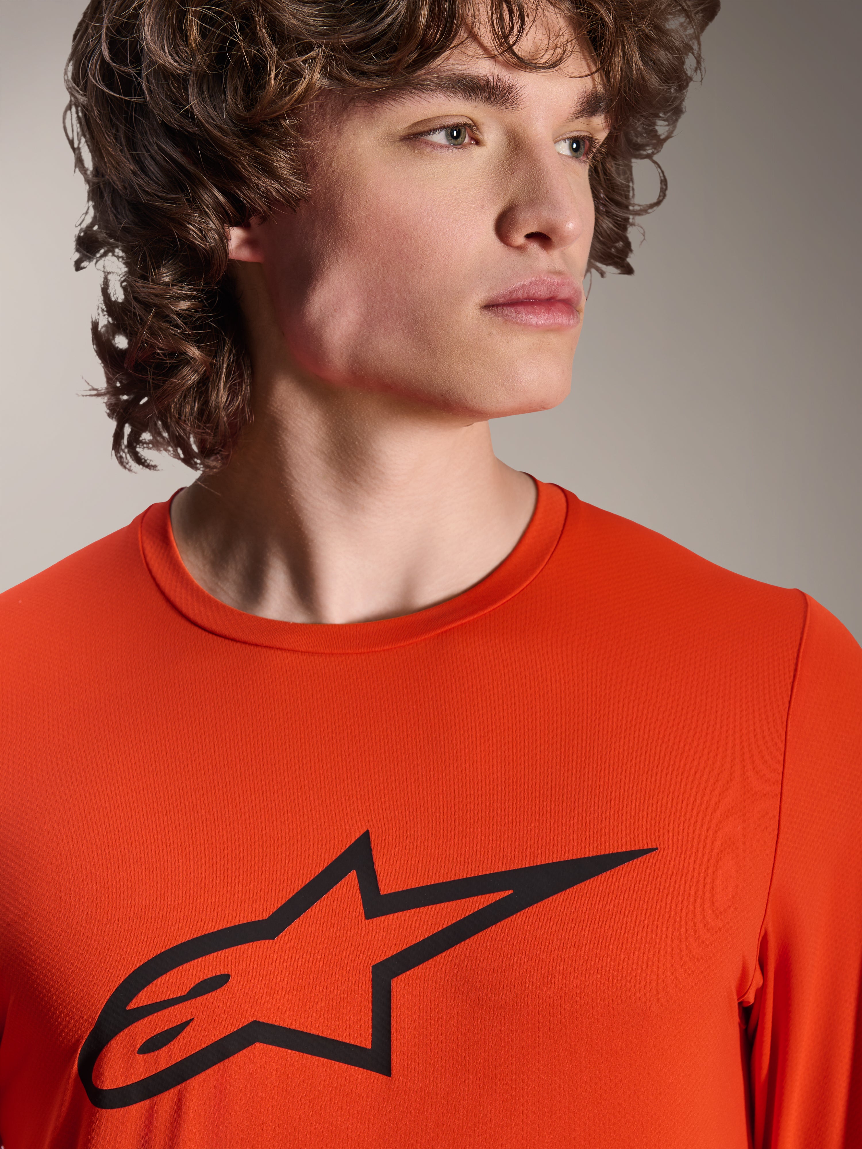Alpinestars A-Dura Insert Astar Jersey, langærmet MTB-trøje, Spicy Orange, med sort Alpinestars Astar-logo på brystet, nærbillede af en mandlig model