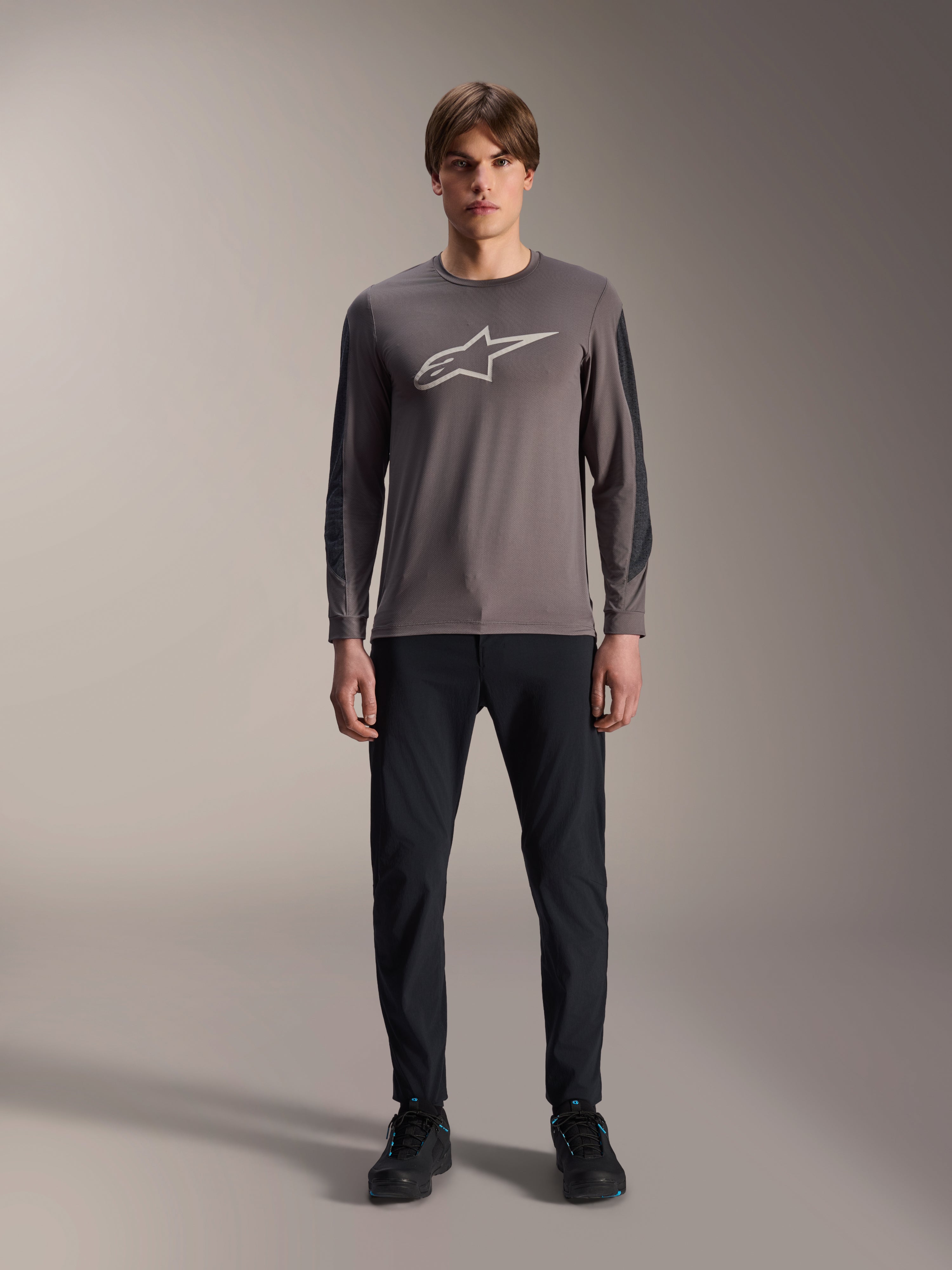 Alpinestars A-Dura Insert Astar jersey, langærmet MTB-trøje, mørkegrå, med et markant lysegråt Astar-logo på brystet og mørkere teksturerede ærmeindsatser, båret af en model med sorte bukser og sko, performance-udstyr til mountainbiking