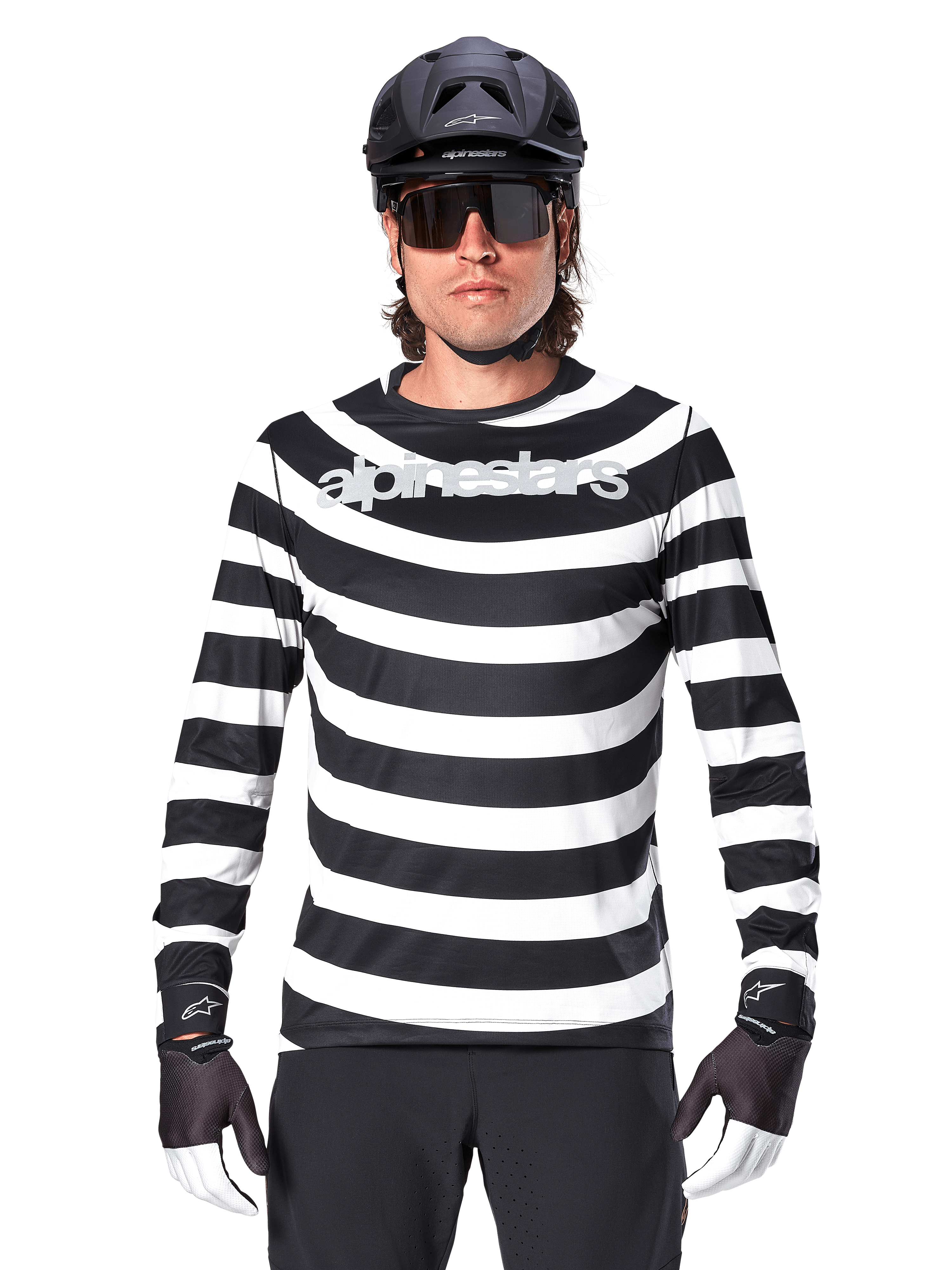 Mandlig cyklist iført Alpinestars A-Aria Oscar langærmet jersey, sorte og hvide vandrette striber, reflekterende Alpinestars-logo på brystet, stylet med sort MTB-hjelm, cykelbriller og performance-handsker