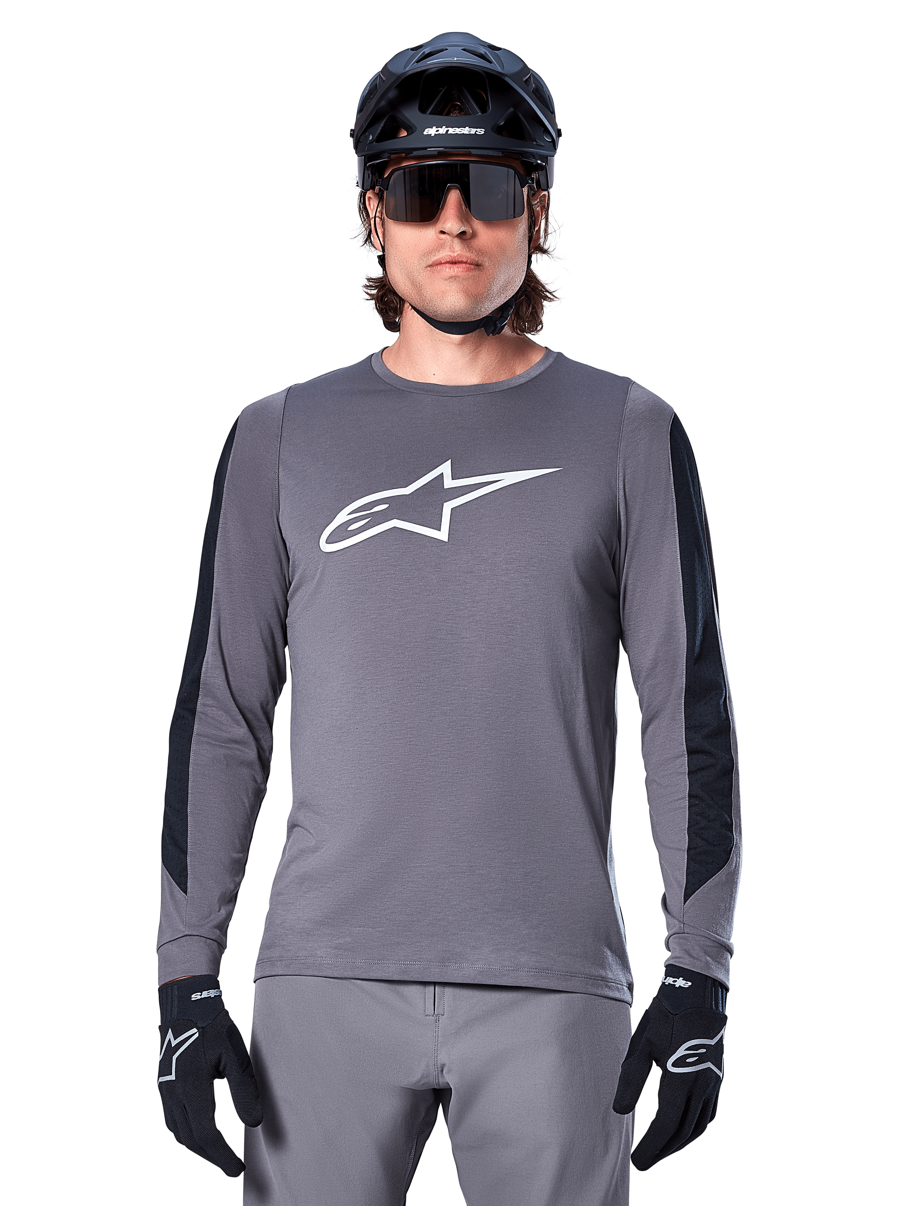 Alpinestars A-Dura Dri Astar langærmet jersey, mørkegrå, med et stort hvidt Astar-logo på brystet og sorte mesh-paneler på armene, båret af en rytter med en sort mountainbikehjelm og performance-solbriller, MTB-cykeltøj