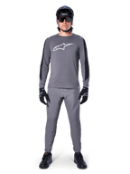 Alpinestars A-Dura Dri Astar Jersey, langærmet MTB-trøje i mørkegrå, med hvidt brystlogo og sorte ærmepaneler, her vist med matchende grå bukser, sort hjelm, solbriller og handsker som et komplet off-road cykeloutfit