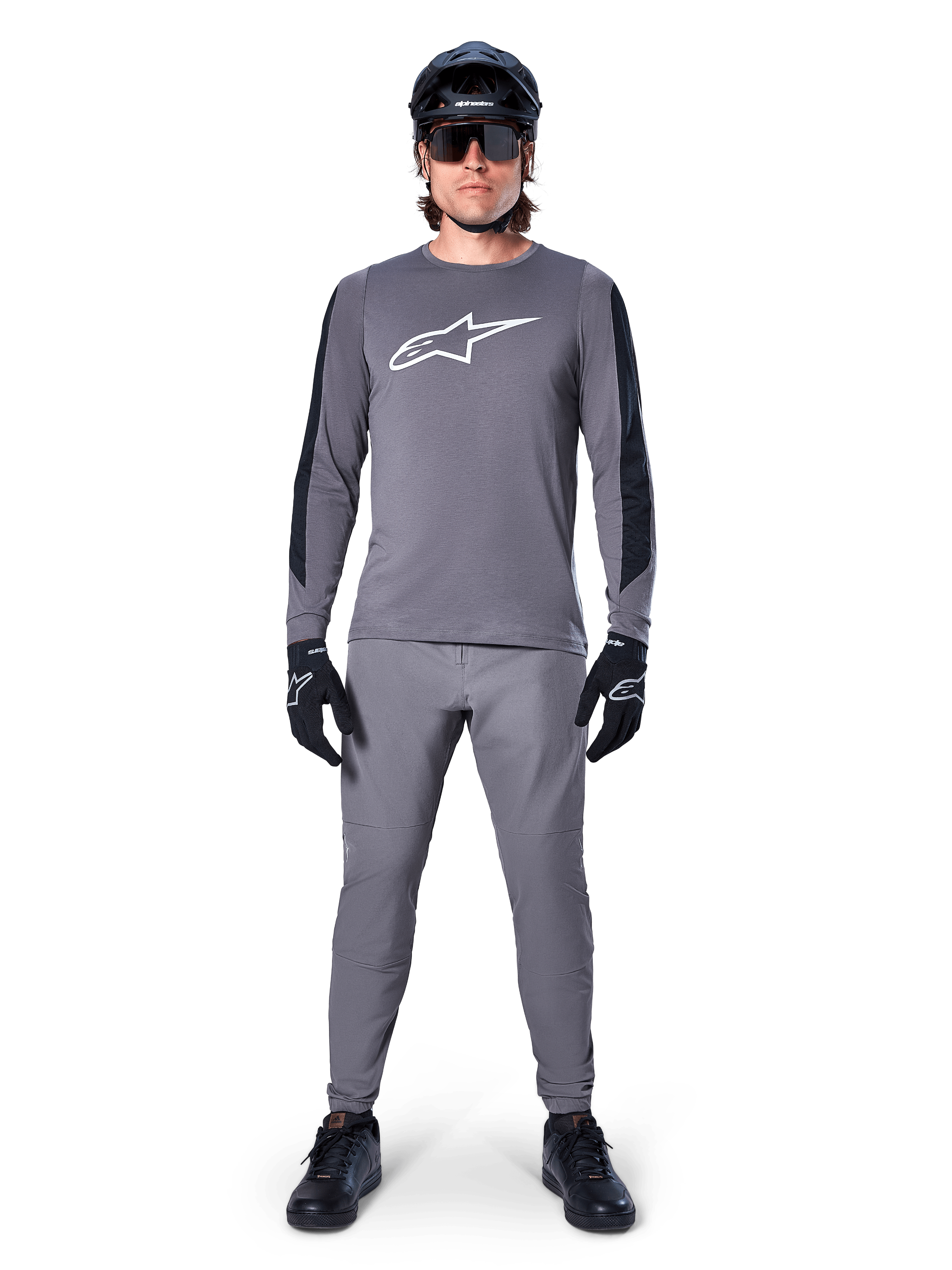 Alpinestars A-Dura Dri Astar Jersey, langærmet MTB-trøje i mørkegrå, med hvidt brystlogo og sorte ærmepaneler, her vist med matchende grå bukser, sort hjelm, solbriller og handsker som et komplet off-road cykeloutfit