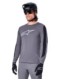 Alpinestars A-Dura Dri Astar langærmet jersey, mørkegrå med hvidt brystlogo og sorte mesh-sidepaneler, MTB mountainbike-trøje, vist med sort hjelm, solbriller og matchende grå bukser