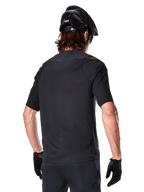 Alpinestars A-Aria Polartec Switch kortærmet trøje, sort, set bagfra på en rytter med sort mountainbikehjelm, matchende sorte shorts og handsker, performance-udstyr til mountainbiking