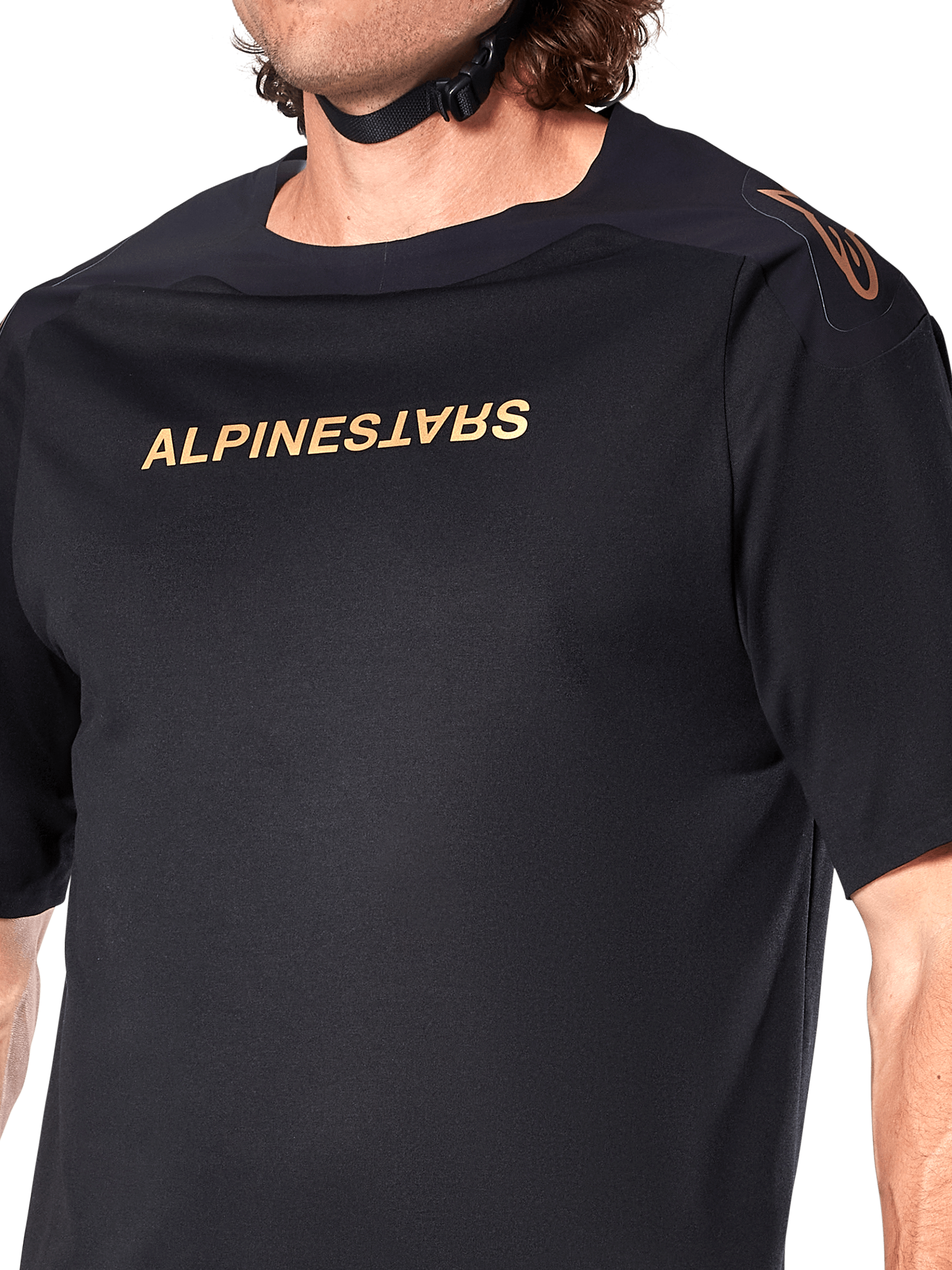 Alpinestars A-Aria Polartec Switch trøje, kortærmet MTB-trøje, sort, guld Alpinestars-skrift på brystet og logo på skulderen, nærbillede af overkroppen, der fremhæver teknisk stof og performance-pasform