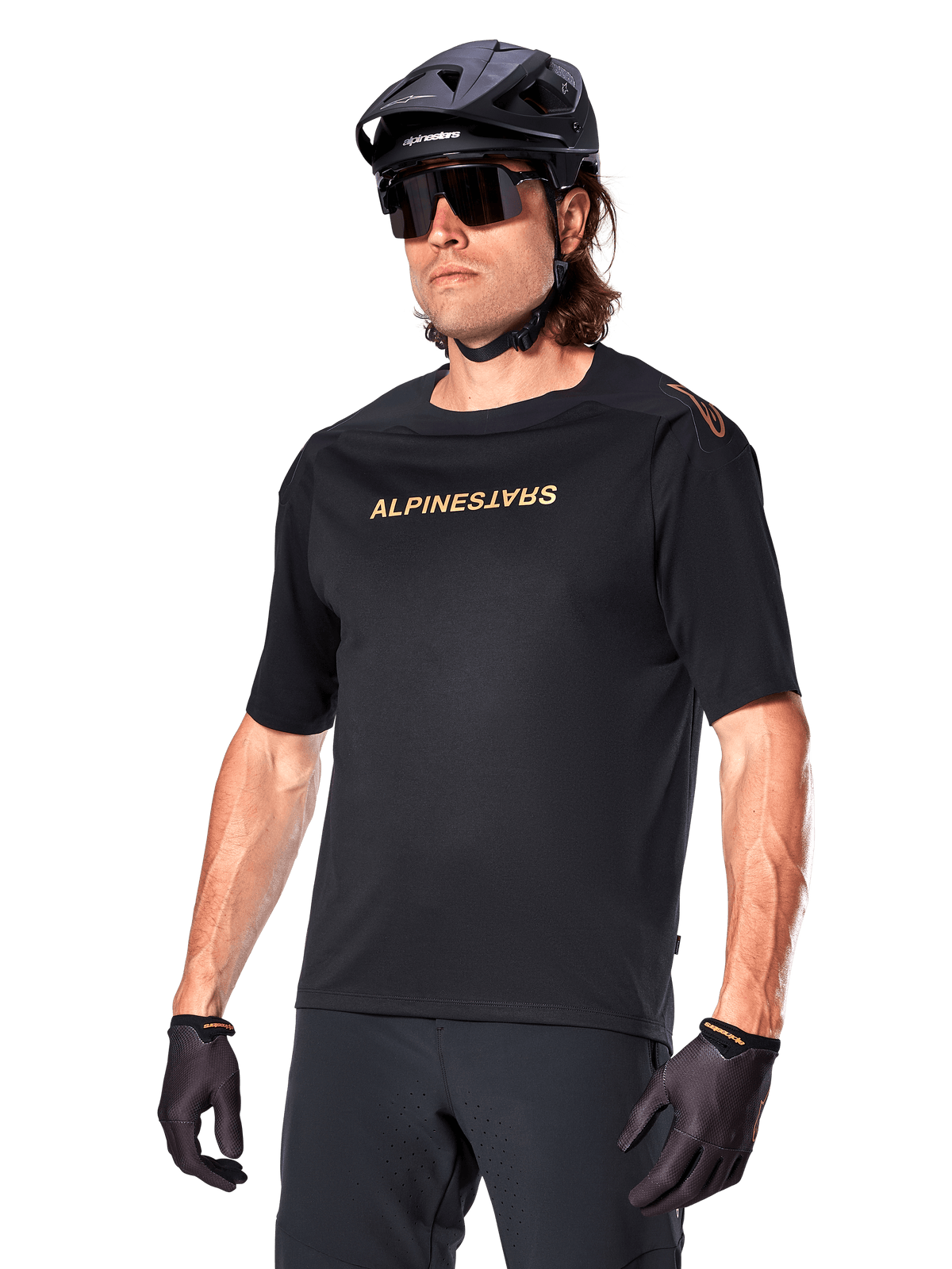 Alpinestars A-Aria Polartec Switch kortærmet cykeltrøje, sort mountainbike-trøje med guld Alpinestars-branding, sort hjelm, solbriller og handsker, teknisk MTB-beklædning