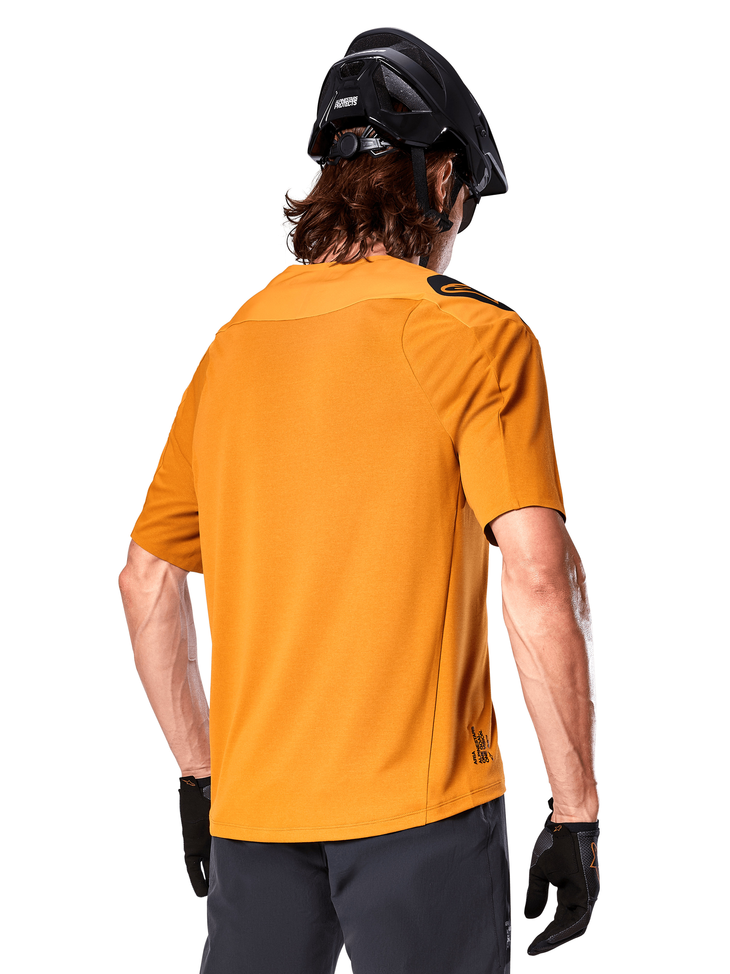 Alpinestars A-Aria Polartec Switch trøje, kortærmet MTB-trøje, mørkeguld, set bagfra med performance fit, båret med sort hjelm og grå shorts, slidstærkt og åndbart udstyr til trail-kørsel