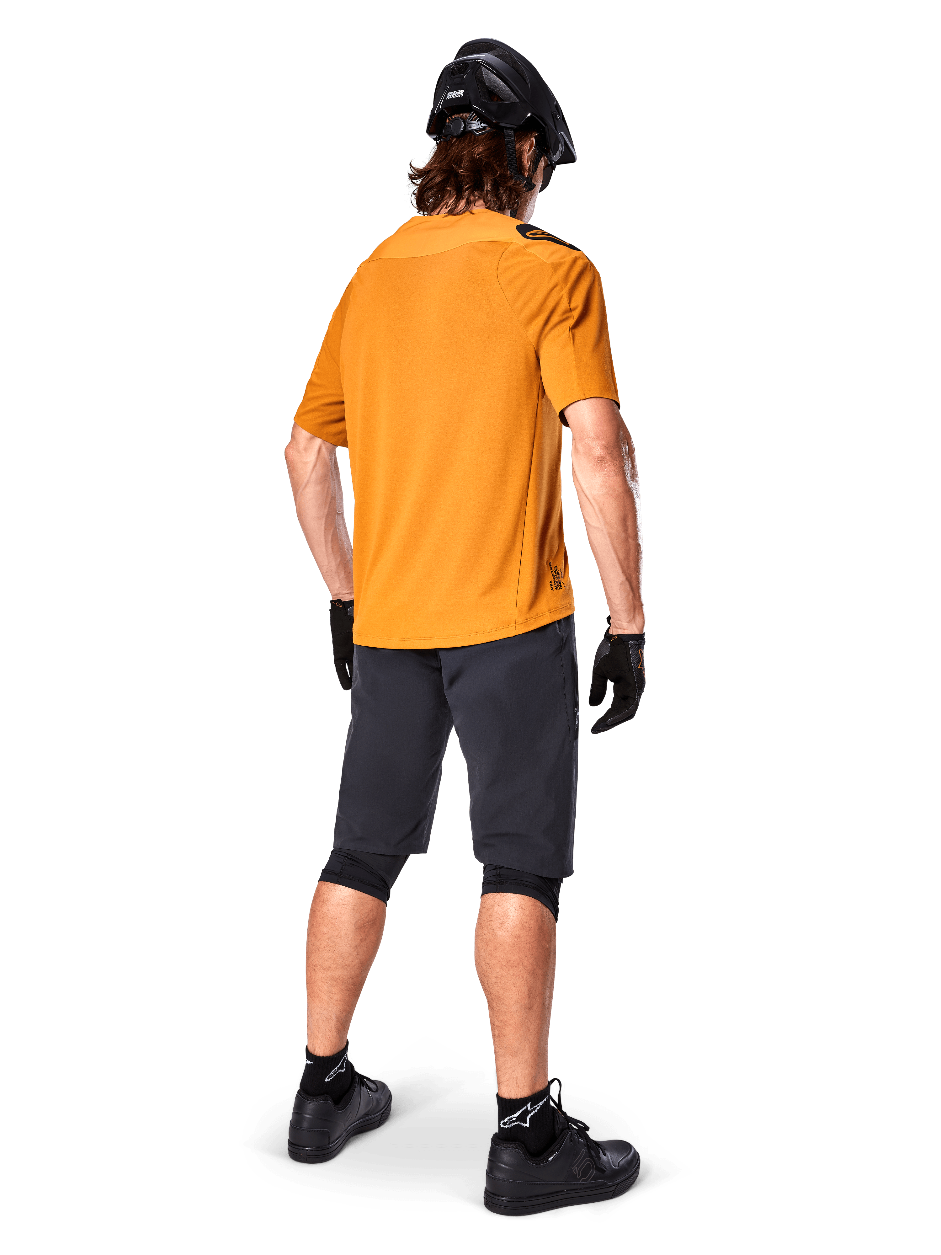Alpinestars A-Aria Polartec Switch-trøje, kortærmet MTB-trøje, Dark Gold, set bagfra af model iført mørkegrå mountainbike-shorts, sort hjelm og handsker, teknisk cykeltøj til off-road stier