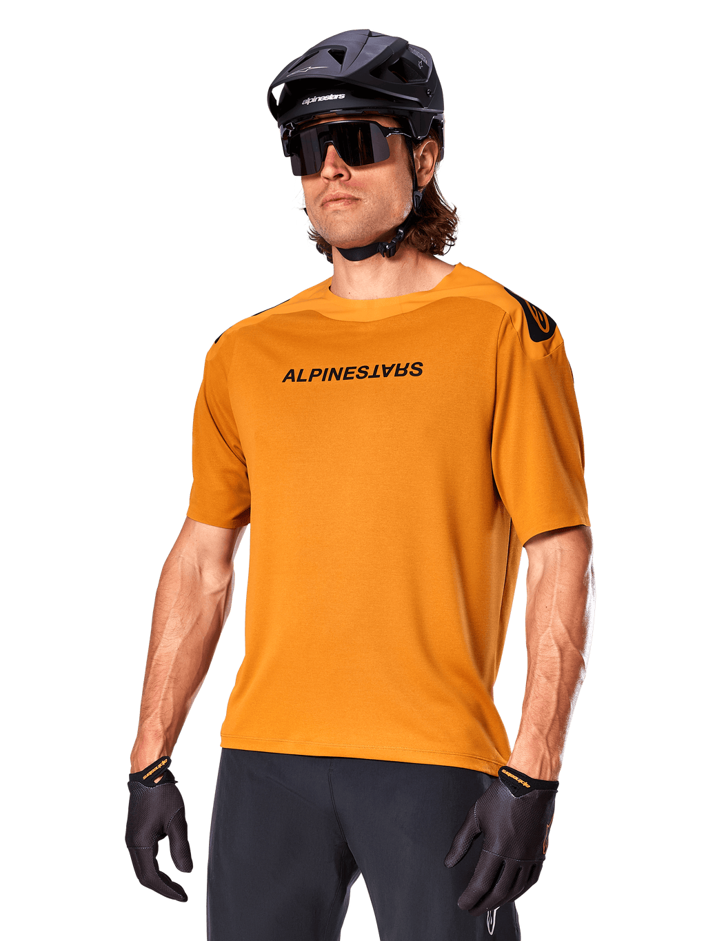 Alpinestars A-Aria Polartec Switch-trøje, kortærmet MTB-trøje, mørk guld med sort branding, båret af model med sort hjelm, solbriller og cykelhandsker, højtydende mountainbike-beklædning