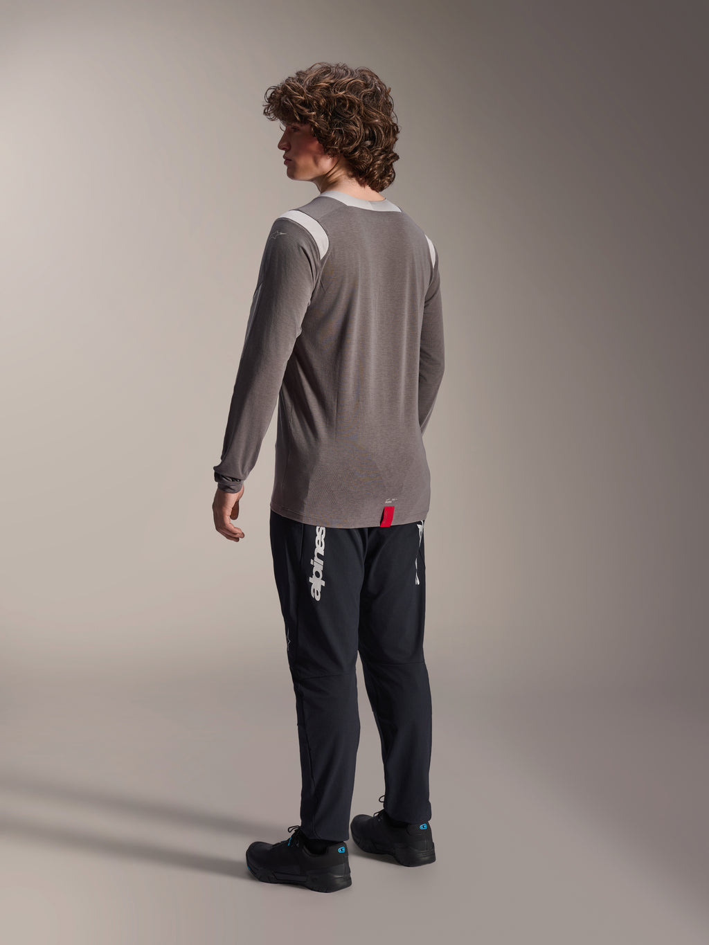 Alpinestars A-Dura Dri-Wool langærmet jersey i grå kombineret med A-Dura Elite bukser i sort, model set bagfra, med hvidt Alpinestars-logo på benet, teknisk mountainbike-udstyr til off-road kørsel