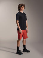 Mandlig model iført Alpinestars A-Dura Elite-shorts i Dark Orange og A-Dura Dri Wool-kortærmet jersey i sort, performanceudstyr til mountainbike, kombineret med sorte sokker og sko, atletisk design til off-road cykling.