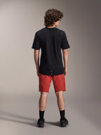 Mandlig model iført Alpinestars A-Dura Elite shorts i Dark Orange og en sort A-Dura Dri Wool kortærmet jersey, set bagfra, kombineret med sorte strømper og cykelsko, professionelt mountainbike-tøj