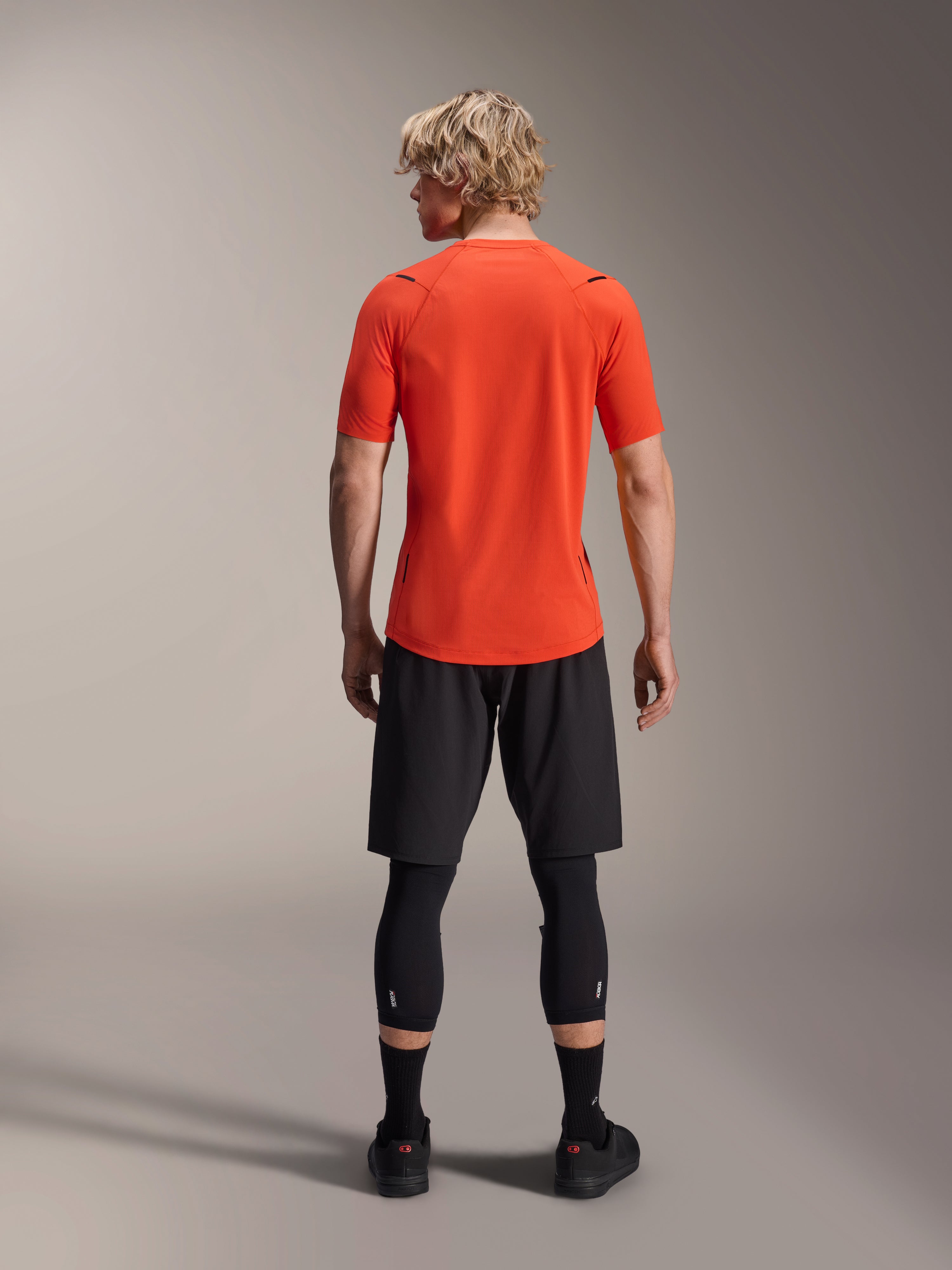 Alpinestars A-Aria Astar jersey, kortærmet MTB-trøje, Spicy Orange, set bagfra, viser performance fit og længere fald bagpå, kombineret med sorte cykelshorts og leggings