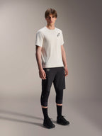 Alpinestars A-Aria Astar trøje, kortærmet, Ecru, med sort logo på brystet, båret med sorte cykelshorts og knæbeskyttere, letvægts MTB-performanceudstyr