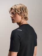 Mand iført Alpinestars A-Aria Switch Jersey, kortærmet, sort, set fra siden og bagfra, der viser performance-fit og skulderdetaljer, letvægts åndbart MTB-cykeltøj
