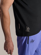 Alpinestars A-Aria Switch Kortærmet Jersey, sort MTB-trøje, nærbillede af sidekant med hvid 'ONE GOAL. ONE VISION.'-branding, båret med lyslilla cykelshorts med matchende logoer