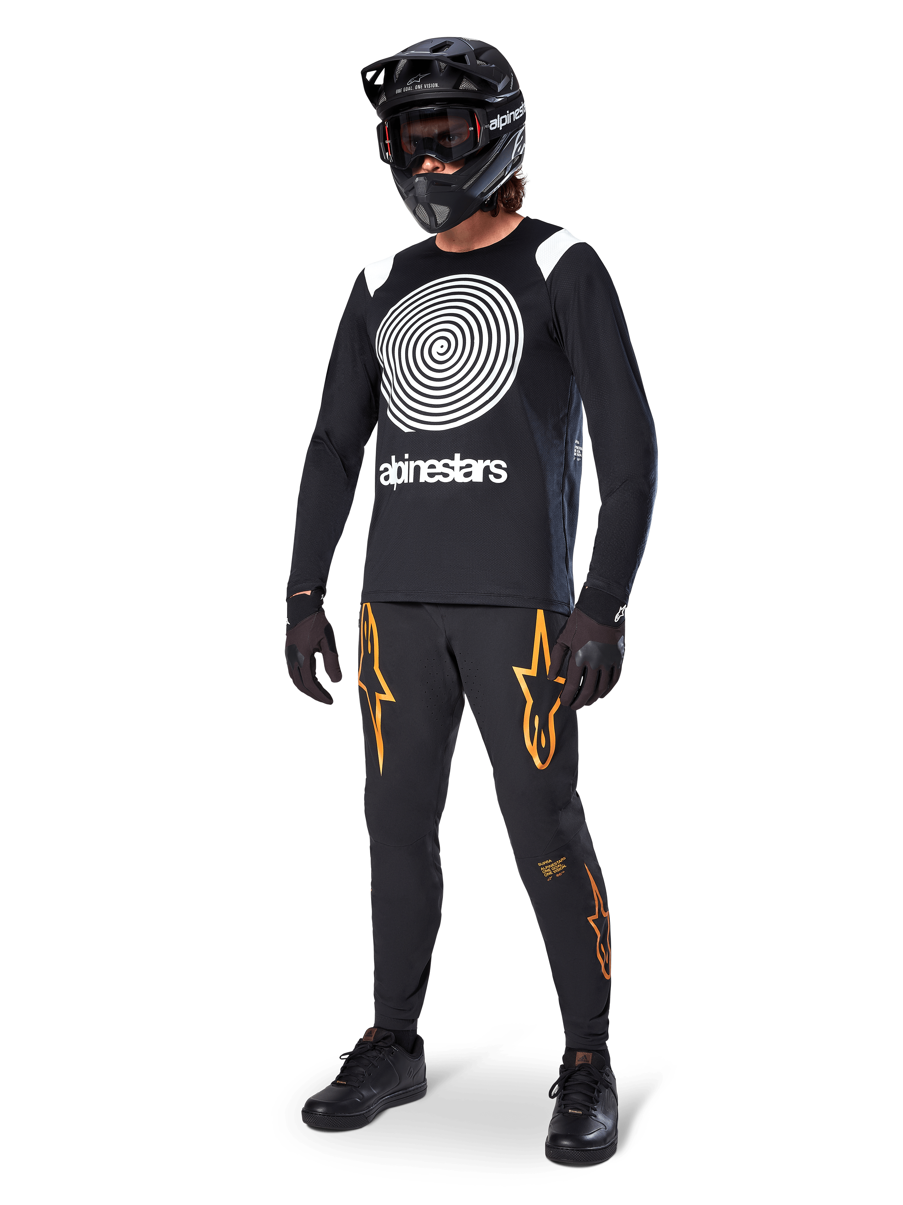 MTB-rytter iført Alpinestars A-Supra Oscar langærmet trøje i sort med hvid vintage Oscar-spiralgrafik, sorte bukser med orange stjernelogoer, sort full-face hjelm med goggles og sorte handsker, professionelt mountainbike-udstyr