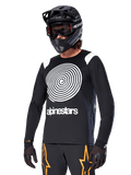 Alpinestars A-Supra Oscar langærmet trøje, MTB-cykeltrøje, sort og hvid, med et markant hvidt spiraldesign og Alpinestars-logo på brystet, båret med en sort full-face hjelm og goggles, performance-beklædning til mountainbike