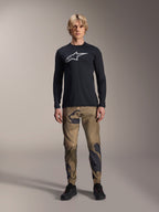 Alpinestars A-Dura Camo bukser, MTB-cykelbukser, brun og grøn camouflage, båret med en sort langærmet jersey og sorte sko, sporty mountainbike-stil med slidstærkt strækstof