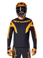 MTB-rytter iført Alpinestars A-Supra Race Jersey - langærmet, sort med orange grafik og brystlogo, båret med matchende orange full-face hjelm, sorte goggles og orange handsker, koordineret racersæt til mountainbike-performance