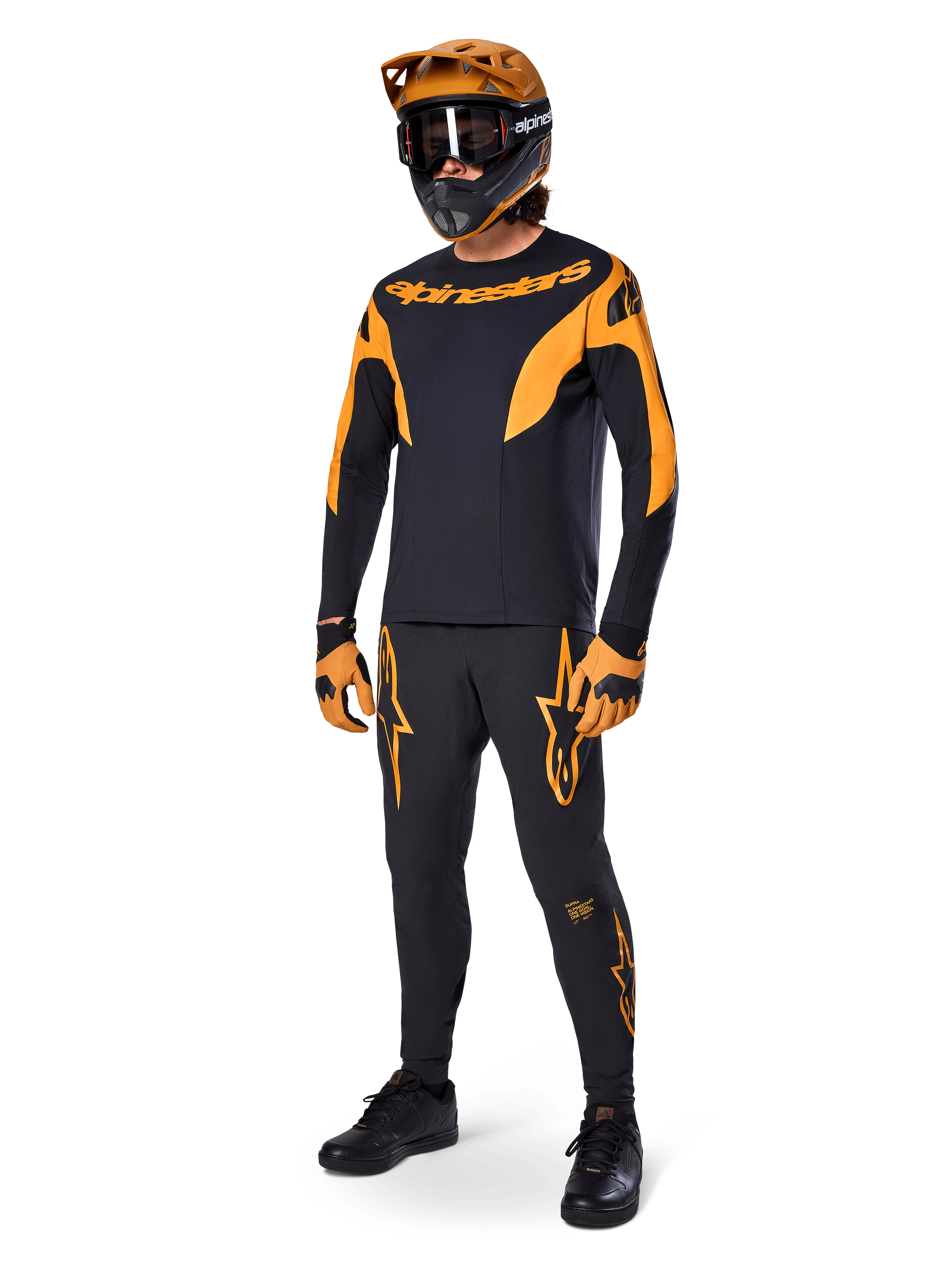 MTB-rytter iført komplet racerudstyr, sort A-Supra Race-trøje med orange detaljer, matchende sorte bukser med orange Alpinestars-logoer, orange og sort full-face-hjelm med goggles, orange og sorte handsker, koordineret outfit til mountainbike-løb