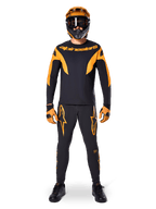 MTB-rytter iført Alpinestars A-Supra Race langærmet trøje i sort og orange, matchende sorte og orange bukser, handsker og en full-face hjelm med goggles, koordineret mountainbike-udstyr til racing og off-road performance