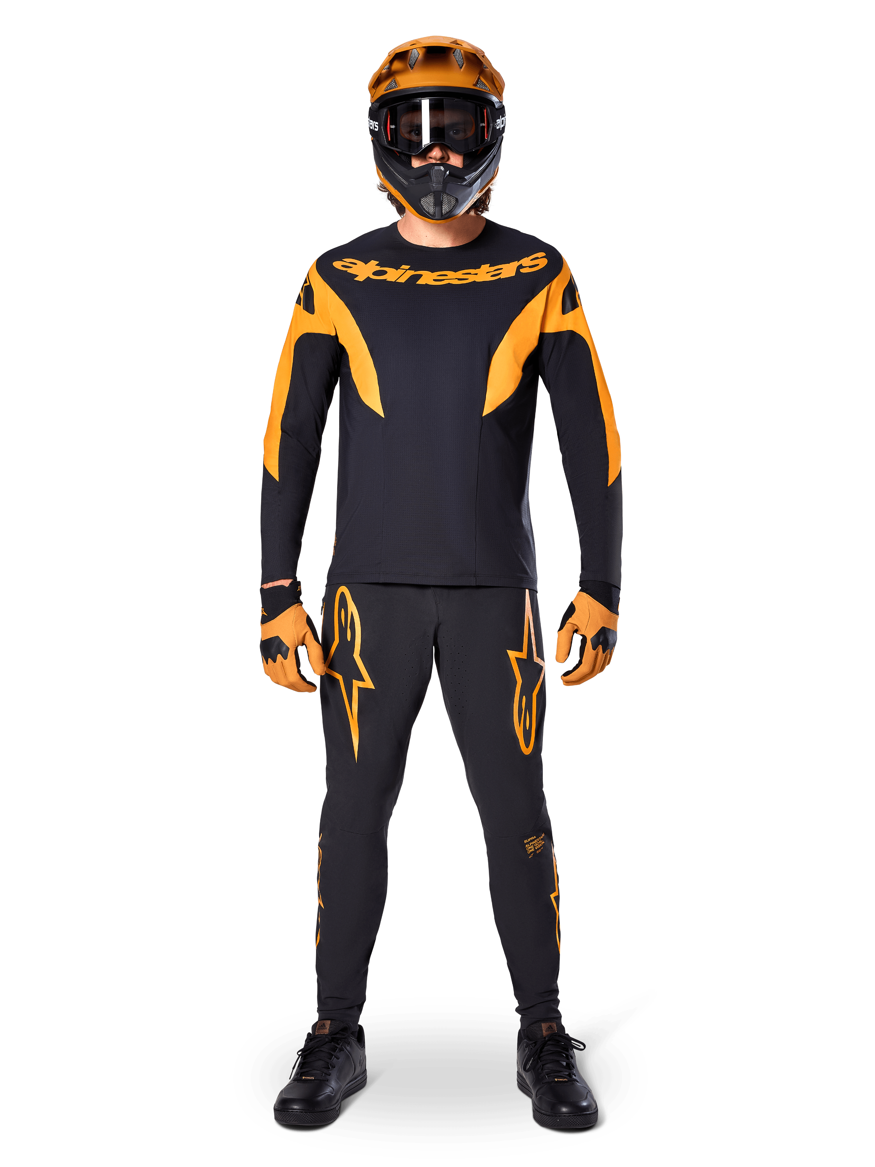 MTB-rytter iført Alpinestars A-Supra Race langærmet trøje i sort og orange, matchende sorte og orange bukser, handsker og en full-face hjelm med goggles, koordineret mountainbike-udstyr til racing og off-road performance