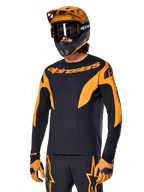 Alpinestars A-Supra Race Jersey – langærmet, MTB-cykeltrøje, sort og orange, båret med matchende hjelm og handsker, Alpinestars-logo på brystet og stiliserede detaljer på ærmerne, performance-pasform til off-road racing