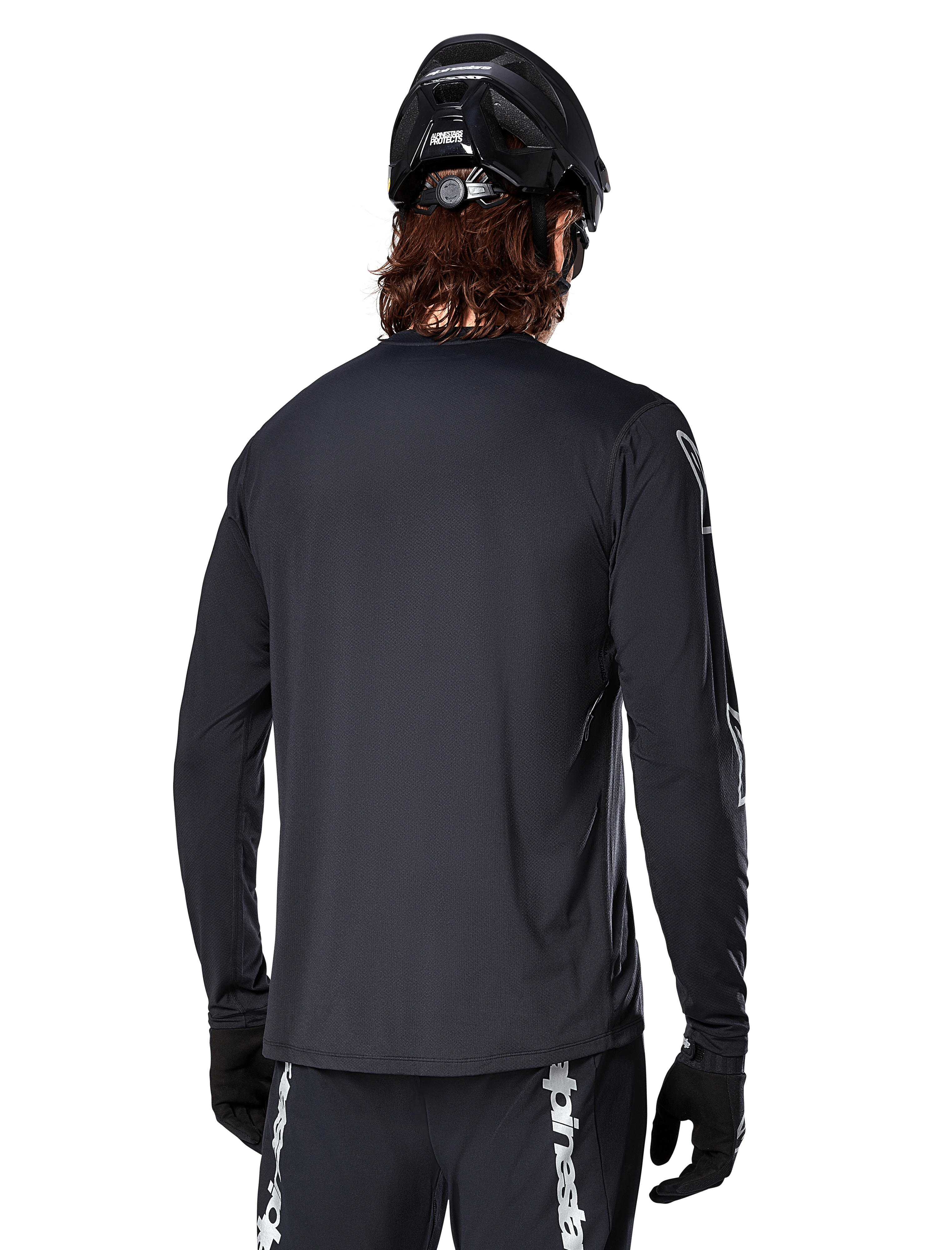 Alpinestars A-Dura Switch Long Sleeve Jersey, Black, rear view on a cyclist wearing a black MTB helmet and gloves, featuring technical jacquard fabric and a drop tail for off-road riding