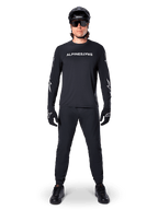Alpinestars A-Dura Switch Long Sleeve Jersey, Black, worn by a mountain bike rider with matching black pants and helmet, featuring white wordmark logo on the chest, technical off-road cycling apparel