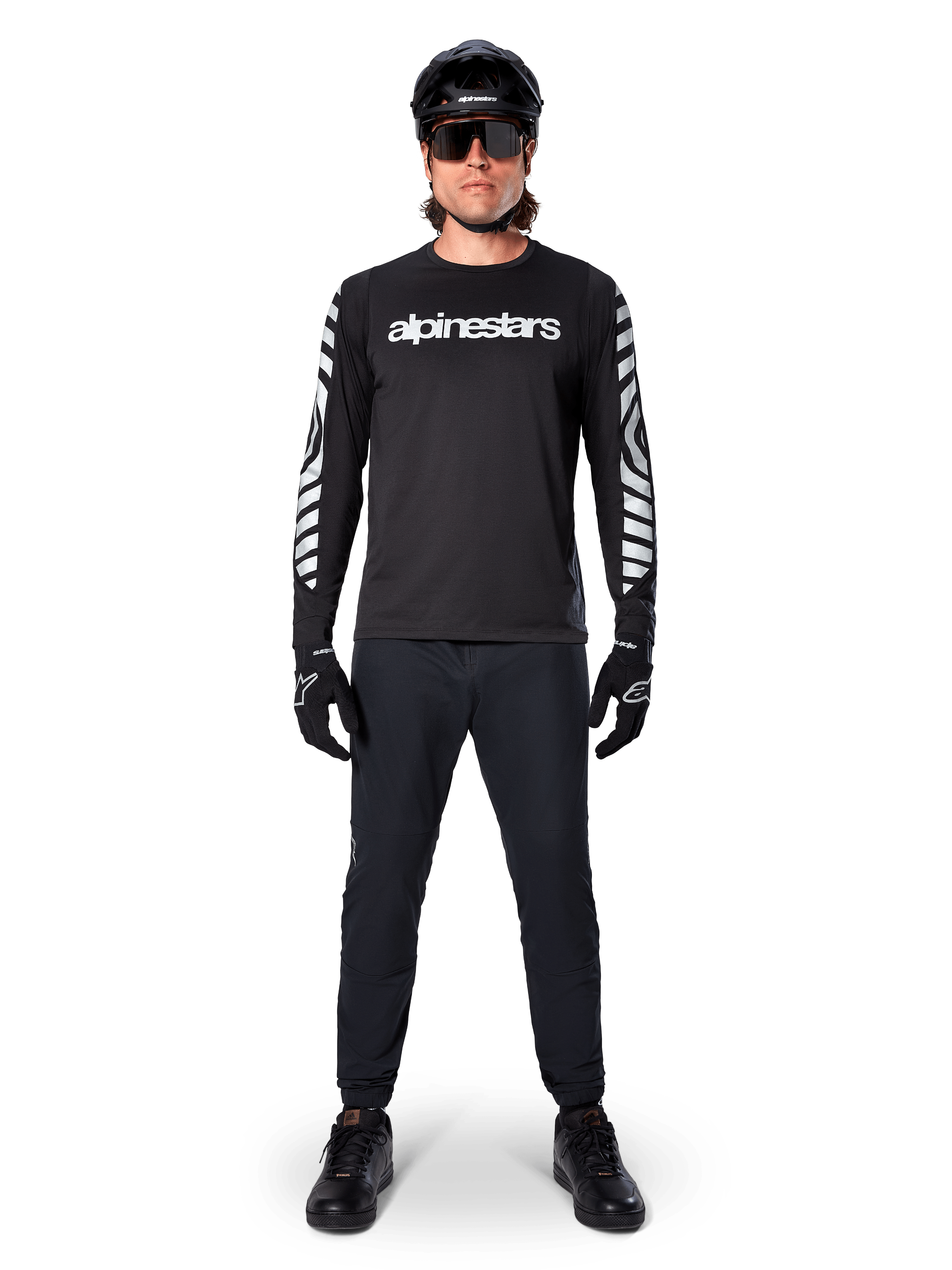 Alpinestars A-Dura Dri Oscar Long Sleeve Jersey in Black Reflective, worn with a black helmet and sunglasses, featuring white chest logo and reflective graphic patterns on the sleeves, MTB gear for off-road riding