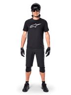 Alpinestars A-Dura Dri Oscar Short Sleeve Jersey, Black Reflective, worn with matching black MTB shorts, gloves, knee pads, and helmet, featuring a large white Alpinestars logo on the chest, complete mountain biking outfit