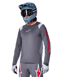 Alpinestars A-Supra Astar Long Sleeve Jersey, MTB Mountain Biking Jersey, Dark Gray with Red and White accents, performance fit, worn with matching gray pants featuring red and white star graphics, complete off-road cycling outfit with full-face helmet and gloves