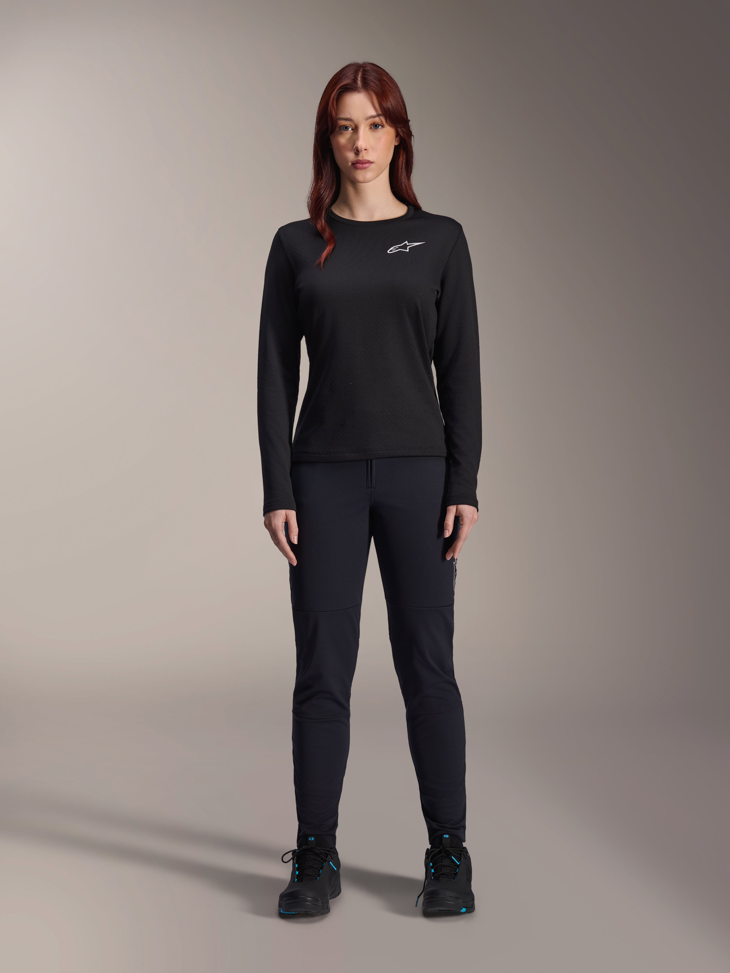 Alpinestars Stella A-Dura Thermal trøje, langærmet mountainbike-trøje til kvinder i sort, med hvidt brystlogo, kombineret med matchende sort udstyr og cykelsko, studioportræt.