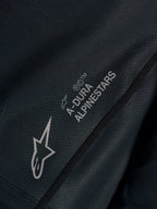 Sort Stella A-Dura Ride trøje, nærbillede af teknisk jacquard-stof med A-DURA ALPINESTARS og Astars-logoer.