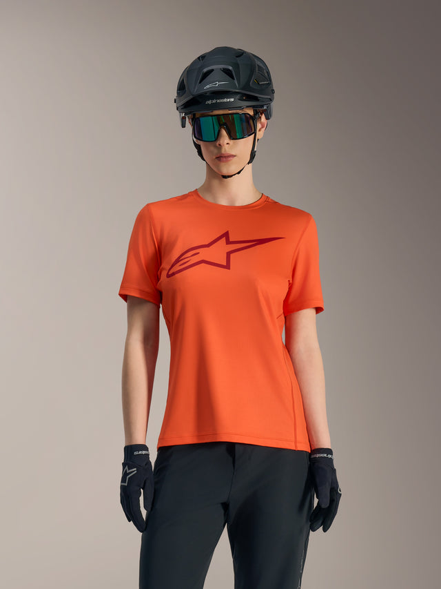 Orange Stella A-Dura Ride kortærmet jersey med rødt logo, kombineret med sort MTB-hjelm og solbriller til kvinder.
