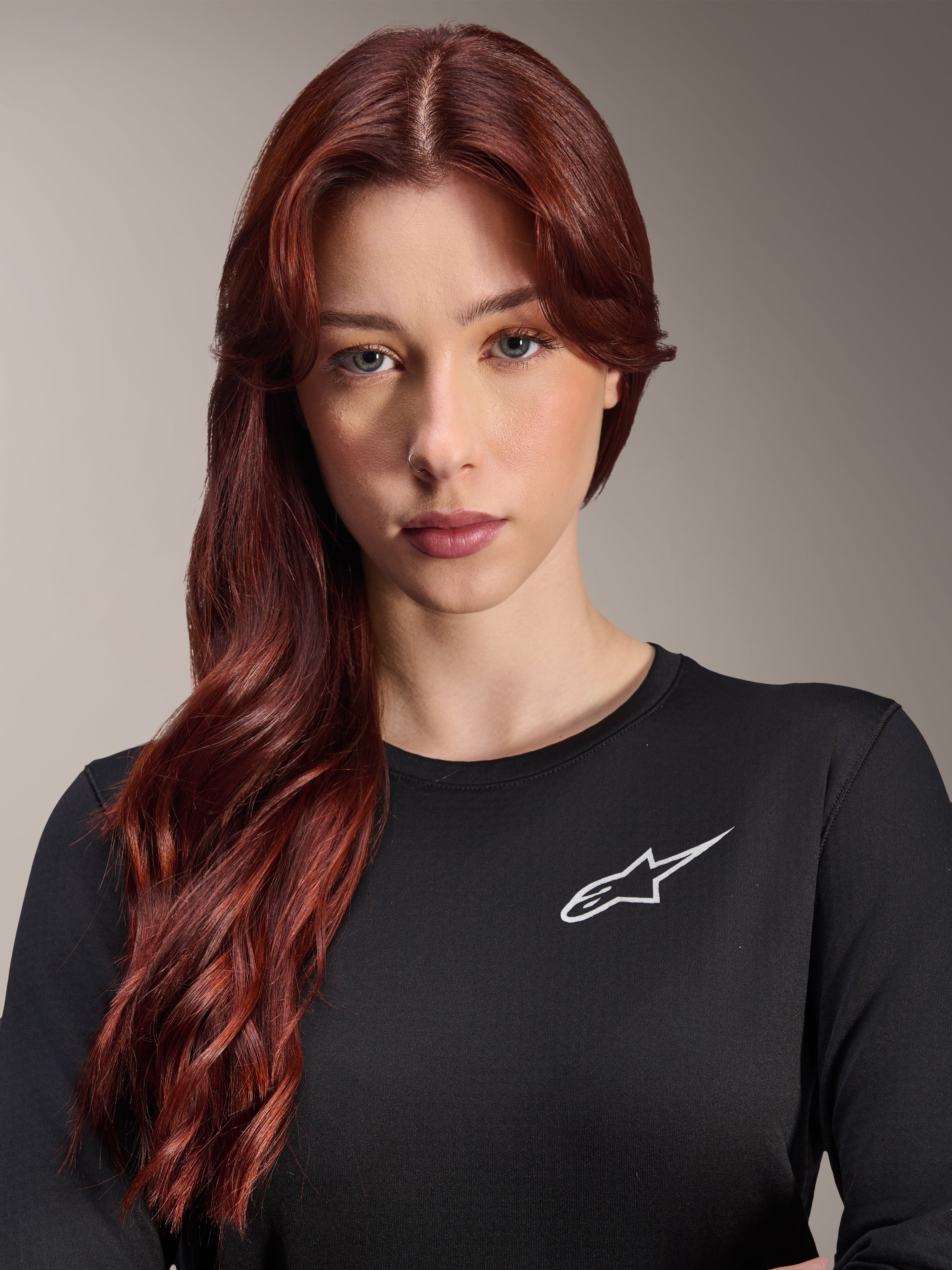 Alpinestars Stella A-Dura Thermal Jersey, langærmet MTB-trøje til damer, sort med hvidt A-star logo på brystet, nærbillede af kvinde med langt rødt hår, cykeltøj til køligt vejr