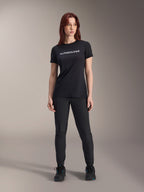 Model wearing Alpinestars Women Stella A-Dura Dri Switch Short Sleeve Jersey in Black, featuring white logo branding on the chest, paired with black technical pants and black athletic shoes, full-body studio shot