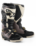 Alpinestars 2026 Tech 7 Enduro Drystar® støvler, motocross- og endurostøvler, sort, mørkegrå og guld, med en robust TPU-skal, hurtigudløselige aluminiumsspænder med gulddetaljer og en stor hvid skinnebensplade med sort logo, designet til off-road holdbarhed.