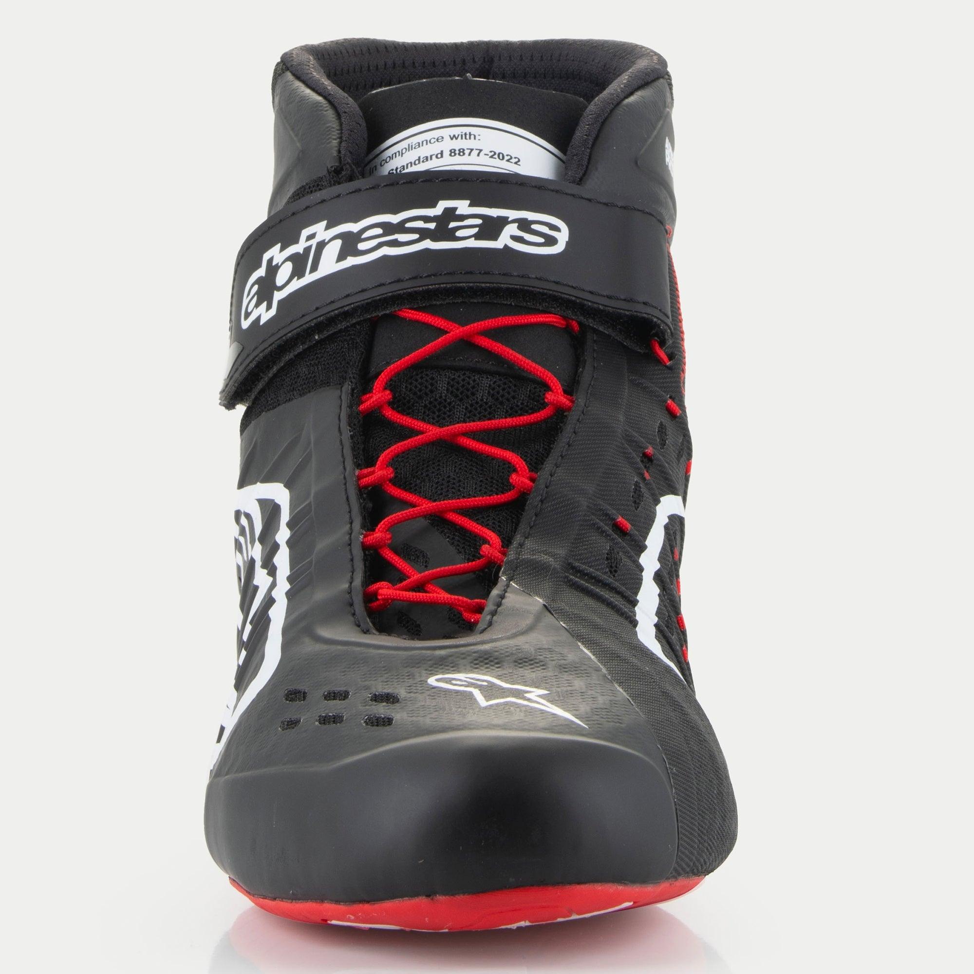 Alpinestars Tech-1 KX V3 sko, karting-sko, sort, hvid og rød, set forfra med røde asymmetriske snørebånd, sort velcro-ankelrem med hvidt logo, FIA 8877-2022 certificeringsmærke synligt på pløsen.