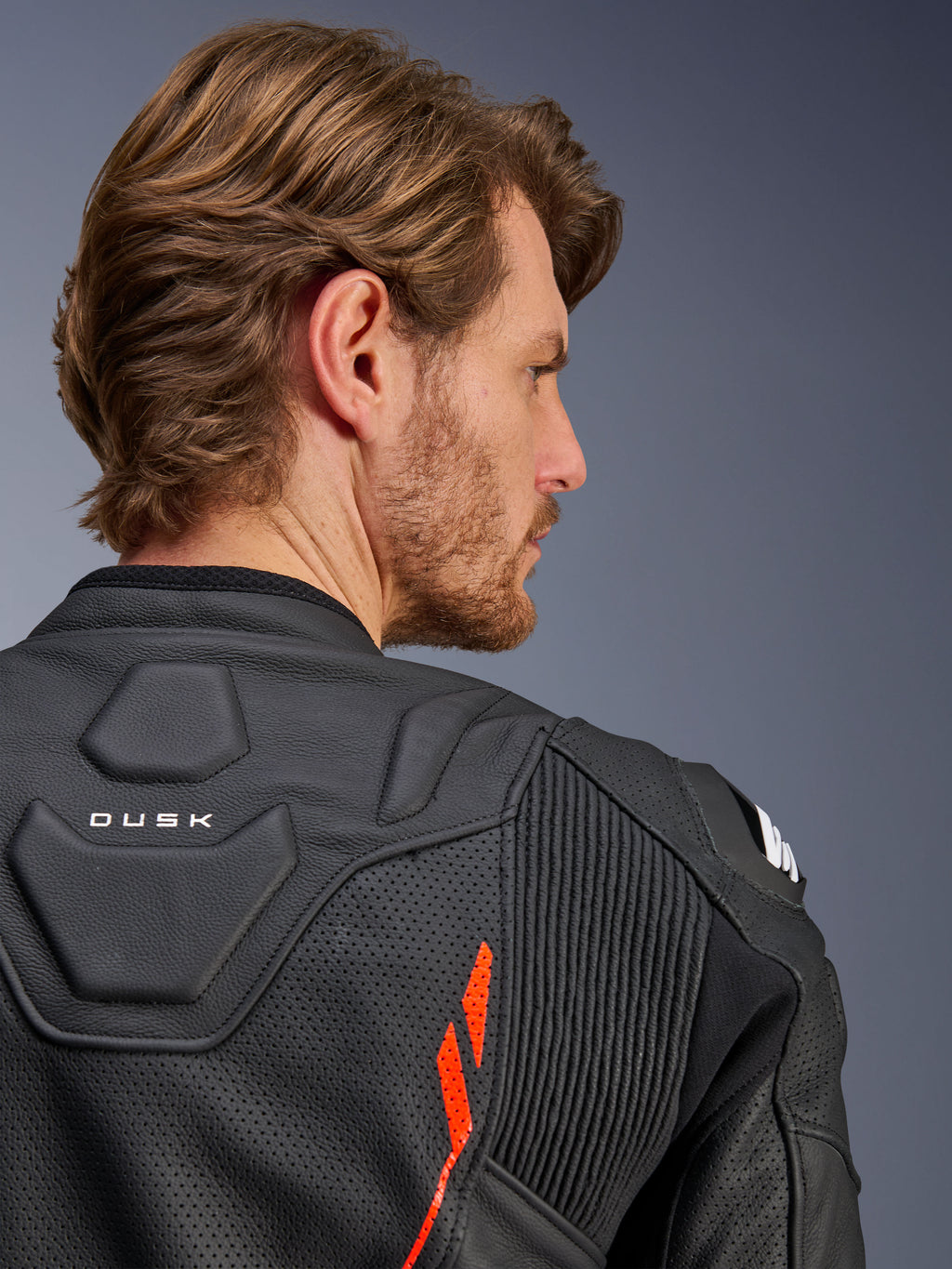 Alpinestars Dusk Airflow læderjakke, Sort Rød Fluo, nærbillede af den øverste del af ryggen og skulderen, med perforeret læder til ventilation og accordion-strækpaneler, 'DUSK' branding-detalje, båret af en mandlig model.