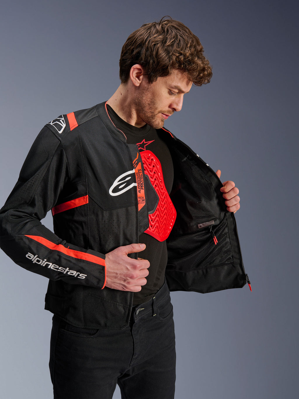 Alpinestars T-Sps Air V2 Jacket in Black and Red Fluo, worn by a model showing the interior mesh and a red Nucleon chest protector, featuring white Alpinestars logos and tech mesh panels