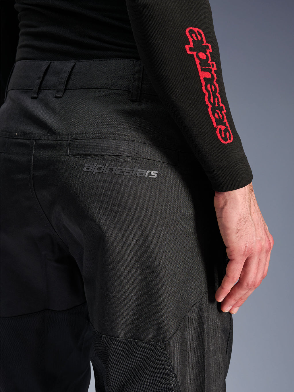 Alpinestars C-1 Air bukser, sorte motorcykelbukser i tekstil, nærbillede af baglommen med et diskret gråt Alpinestars-logo, åndbare mesh-paneler og slidstærkt poly-tekstil, designet til komfort ved bykørsel